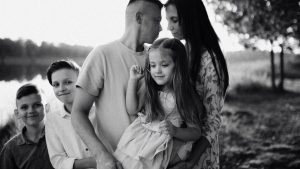 A serene black and white portrait of a family standing by a lake.